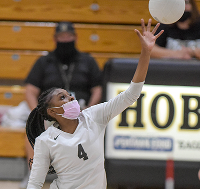 girl tipping volleyball over net