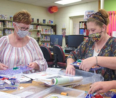 adults sitting at desk working on electronic kits