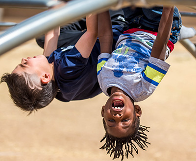 kids hanging upside down on jungle gym