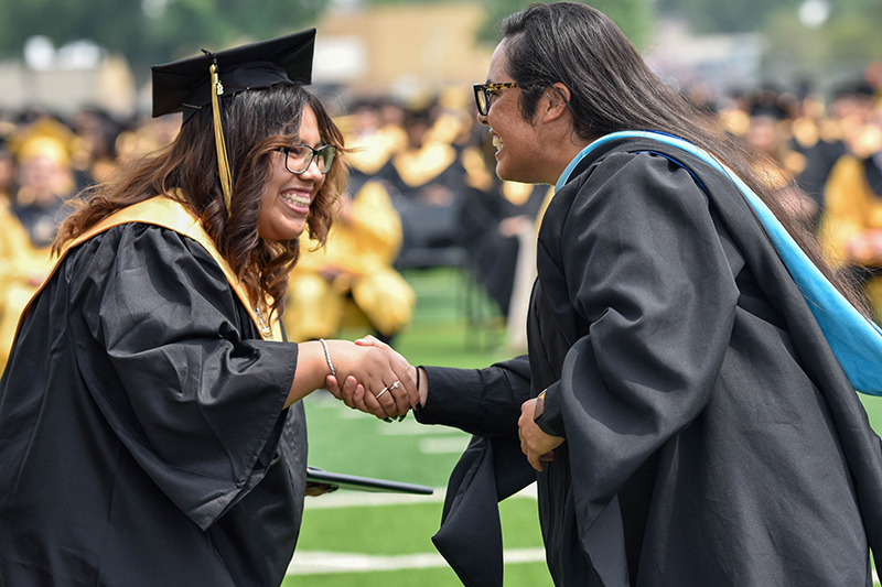 smiling student and teacher shaking hands