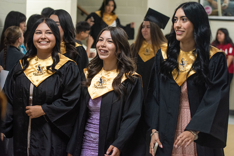 three girls walking down hall in cap and gown