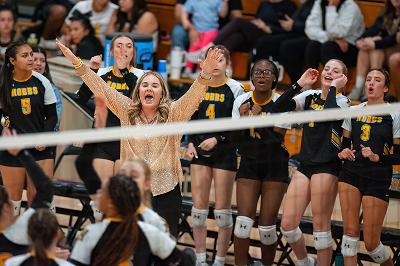 woman with arms in air in front of standing players