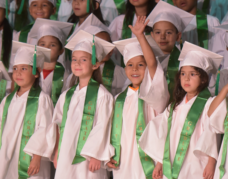 student in crowd of pre-k graduates waving